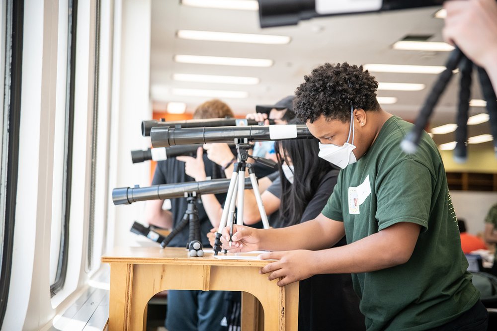 student writes down measurements observed from a telescope