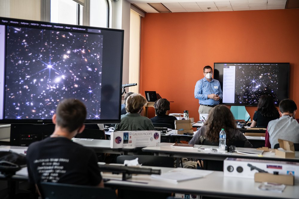 professor lecturing on images of galaxy on screen