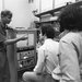 A man is describing something to two other men, standing next to a piece of lab equipment.