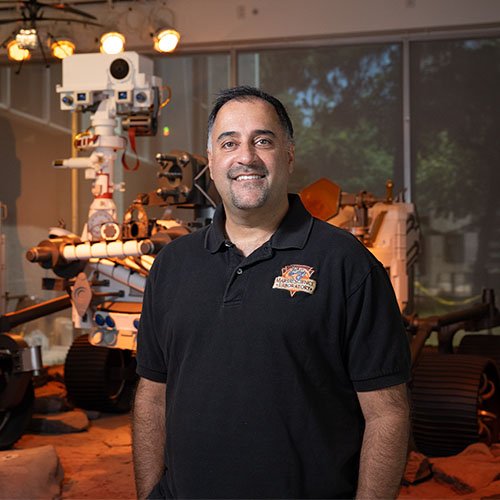 Ashwin Vasavada of JPL standing in front of a replica of the Curiosity Rover