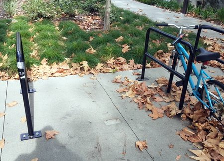 Two bike racks bookend a blank patch of concrete where a third rack has gone missing