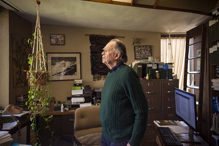 Ted Scudder, professor emeritus of anthropology, stands in his office. He is surrounded by file folders, books, and artifacts.