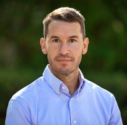 A portrait of Charlie Sprenger. He is outdoors and wears a button-down shirt.