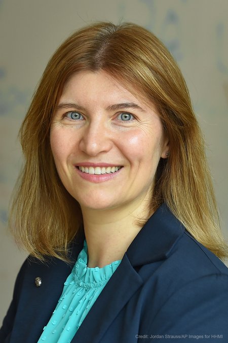 A white woman with a blue blouse and blazer smiles at the camera