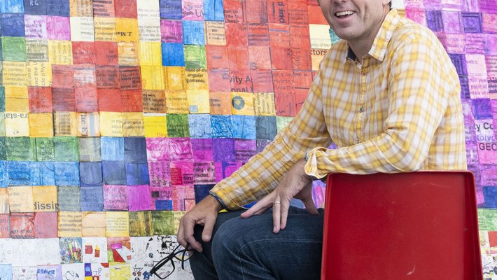 Calum Torrie seated alongside a mosaic of 1,156 science-themed pictures
