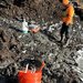 Scientists stand outside near rocky soil.