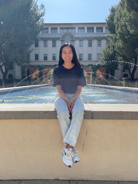 A woman smiles for a photo in front of Caltech's "gene pool" fountain.