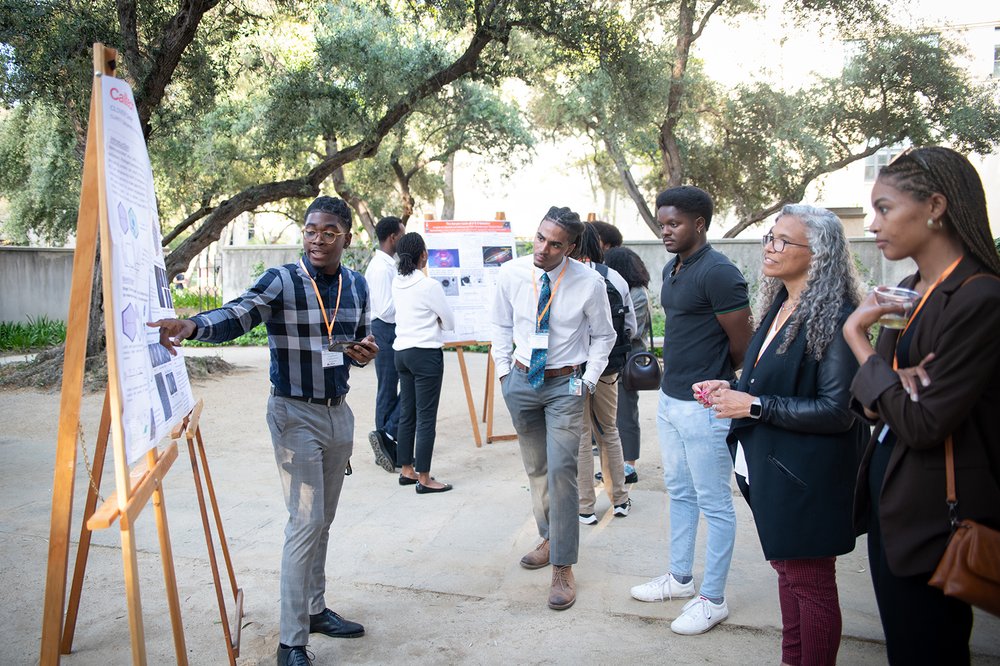 Ayoola Fadonougbo, undergraduate student at CSULB and former Caltech WAVE Fellow, presents research at CEBAS while Cameron Jackson (second from left in image) listens.