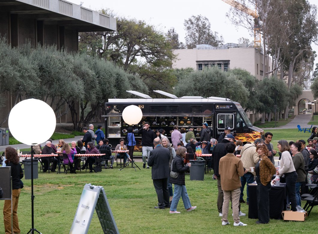 Image of Beckman mall with several people mingling near tables and a food truck