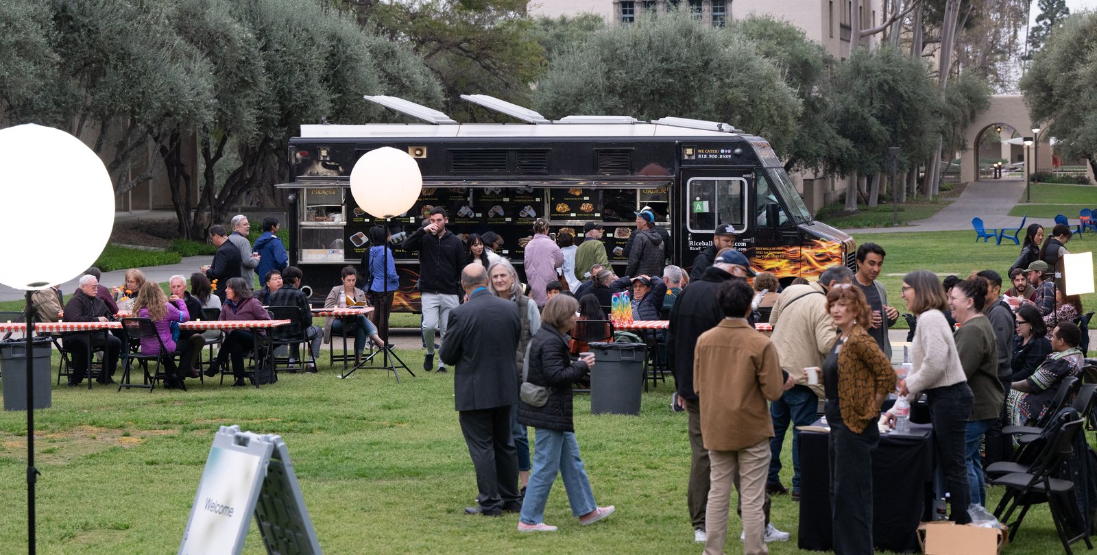 Image of Beckman mall with several people mingling near tables and a food truck