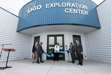 Picture of Amber trunk cutting the blue ribbon in front of the LIGO Exploration Center.