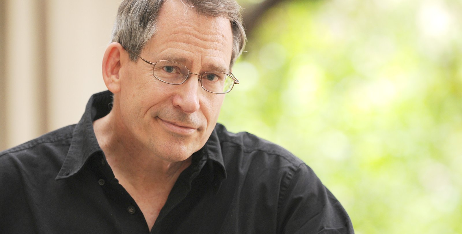 Head shot of John Preskill. He wears wire-rimmed glasses and a black shirt.