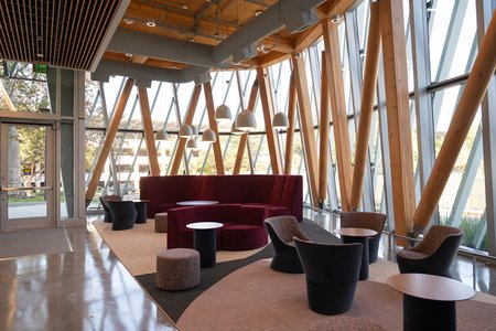 A corner of the RSC is shown, with floor-to-ceiling glass walls, a mass timber frame, and modern furniture and lighting.