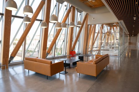 A section of the new RSC building, featuring floor-to-ceiling glass walls, a mass timber frame, and modern furniture. The Beckman Institute can be seen through the windows in the background.