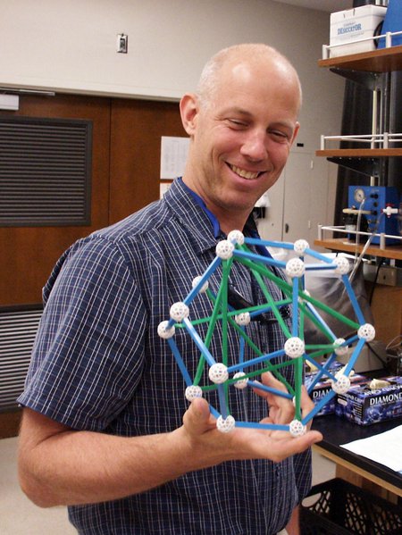 A man holds a plastic molecular model in lab