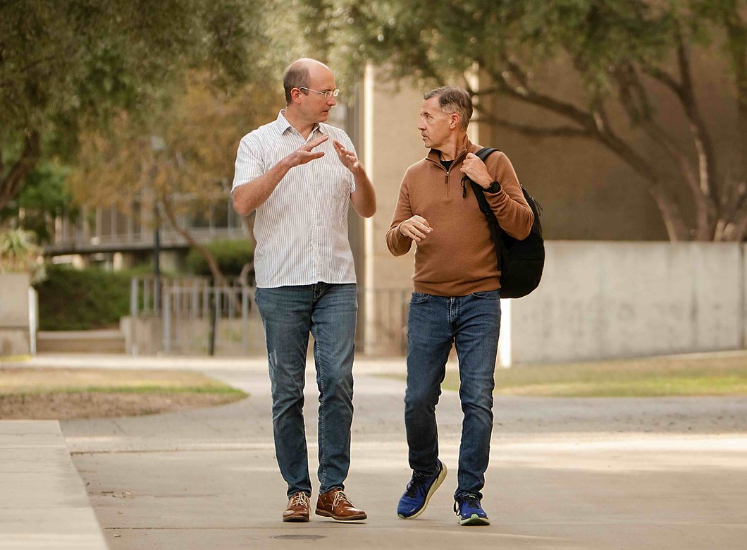 Friedrich Eberhardt and Michael Alvarez walk across Caltech's campus while conversing with one another