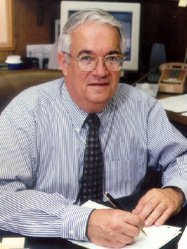 Vince McKoy sits at his desk, wearing a button down shirt and tie.