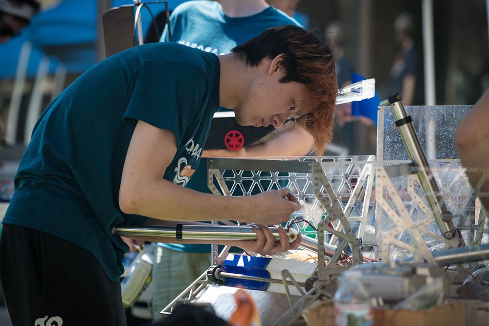 A student team repairs a robot they built for the ME72 competition