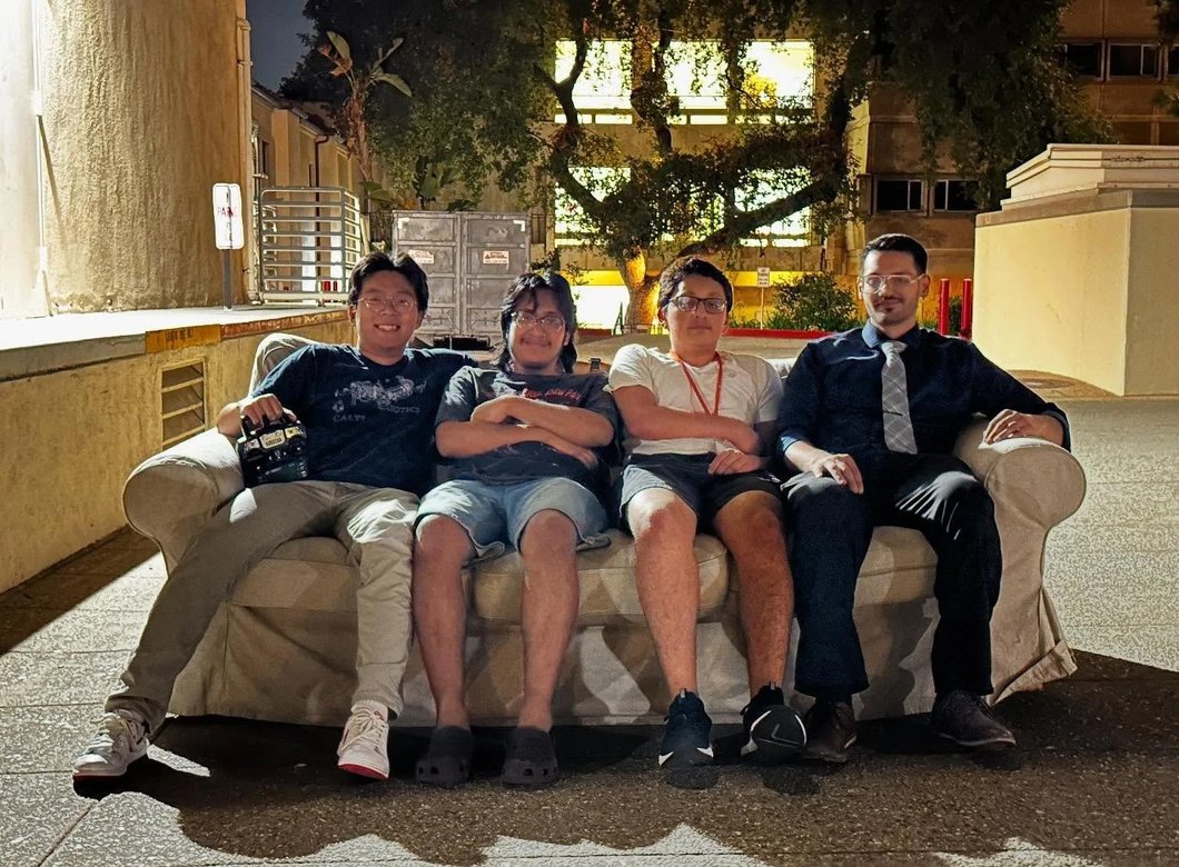 Four Caltech students sitting on a brown couch that they turned into a robot.